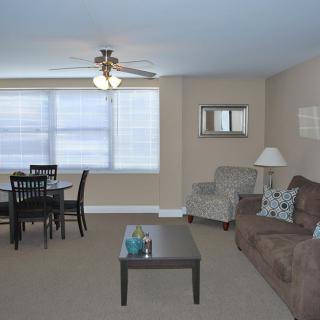 A cozy living room with a sofa, coffee table, dining set, and a ceiling fan.