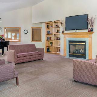 A cozy living room featuring modern furniture, a television above the fireplace, and a piano.