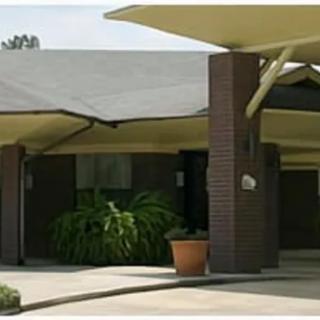 A modern building entrance with angular roof structures and potted plants.