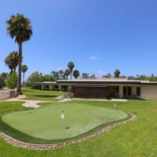 A sunny day on a golf course with a putting green and surrounding palm trees.
