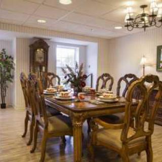 A classic dining room with an elegant wooden table and chairs, complemented by a chandelier and decorative plants.