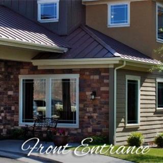 A welcoming front entrance of a residential home featuring brick and siding.