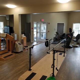 A well-equipped rehabilitation and physical therapy gym featuring walking bars and various exercise machines.
