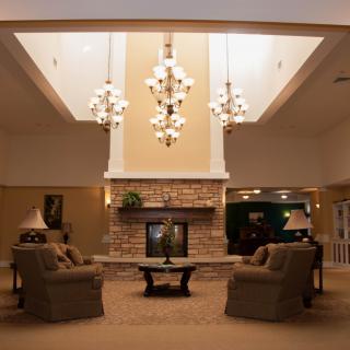 A cozy living room with chandeliers, a central fireplace, and comfortable seating.