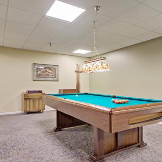A spacious game room featuring a pool table with overhead lighting.