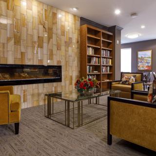 A cozy living room with a modern design, featuring a fireplace, bookshelf, and comfortable seating.