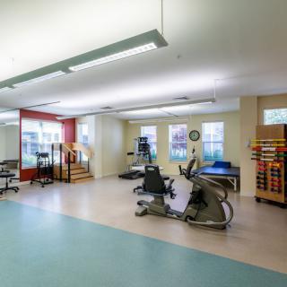 A clean and spacious fitness center equipped with various exercise machines and rehabilitation equipment.