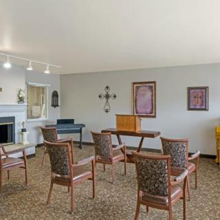 An empty room with an arrangement of chairs and a table, decorated with wall art and a carpeted floor.