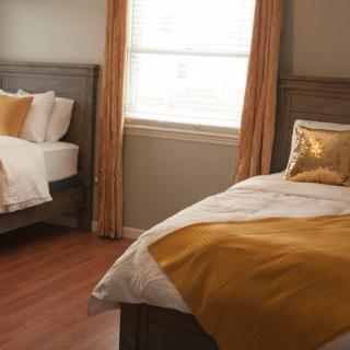 A cozy bedroom featuring twin beds with orange accents and a wooden floor.