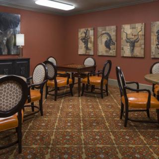 A cozy room with several tables and chairs, adorned with wall artwork and a patterned carpet.
