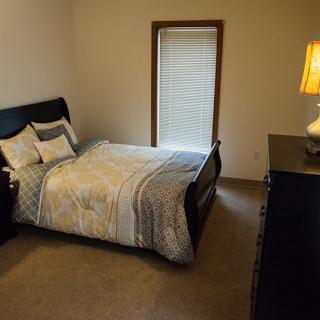 A cozy bedroom with a bed, side lamp, and window.