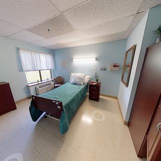 A well-lit and neatly arranged hospital patient room, featuring a single bed and minimalistic furnishings.