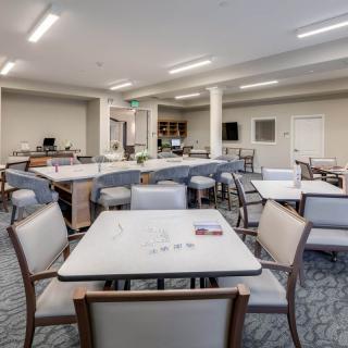 A modern dining area with neatly arranged tables and chairs under bright lighting.