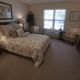 A cozy bedroom featuring a bed with patterned bedding and two chairs by the window.