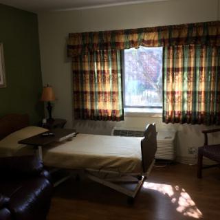 A cozy hospital room featuring a bed, a comfortable chair, and colorful curtains.