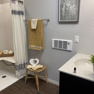 A neatly organized bathroom featuring a sink, shower, and decorative elements like towels and a stool.