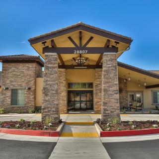 A modern building entrance with a stone facade and clear blue sky.
