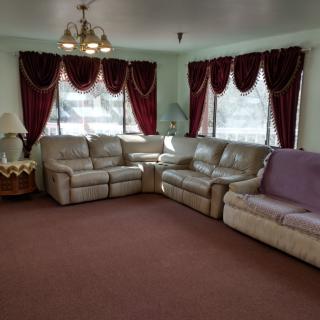 A cozy living room with sofas, red curtains, a chandelier, and a carpet.