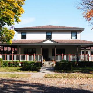 A charming two-story house with a large porch and an autumn setting.