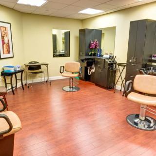 A modern hair salon with stylish chairs and mirrors, featuring a wooden floor and sleek interior design.