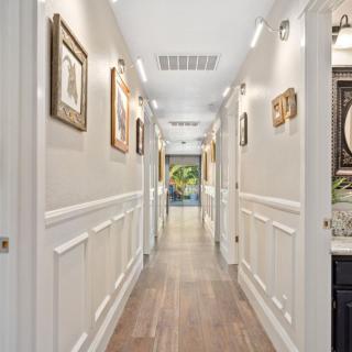 A beautifully decorated hallway with framed artwork and elegant wainscoting.