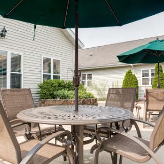 A cozy patio setting featuring a round table surrounded by comfortable chairs and umbrellas for shade.