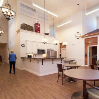 A spacious cafe with high ceilings, chandeliers, and a cozy atmosphere featuring wooden floors and comfortable seating.
