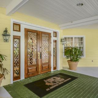 A welcoming entrance with elegant wooden doors and vibrant yellow walls, adorned with greenery.
