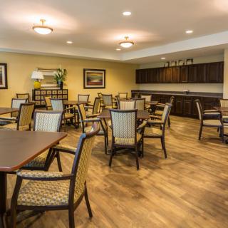 An empty dining area with neatly arranged tables and chairs on a wooden floor.
