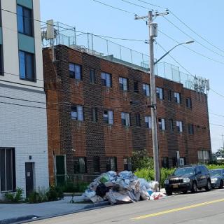 A view of a brick building with some garbage piled up in front, located on an urban street.