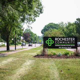 A welcoming sign for Rochester Community set against a lush green landscape.