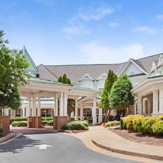 A well-maintained building entrance with landscaping and a circular driveway under a clear blue sky.