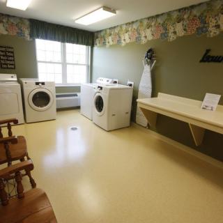 A well-organized laundry room with washing machines, a dryer, and an ironing board.