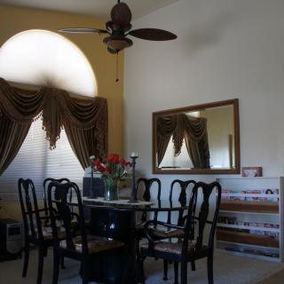 A cozy dining room with a round table, elegant chairs, and decorative curtains.