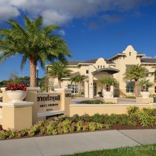 Modern residential building with palm trees and landscaped entrance.