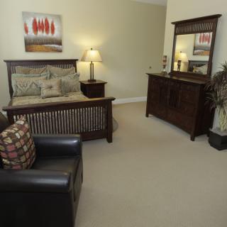 A cozy bedroom with a bed, dresser, mirror, and lamp.