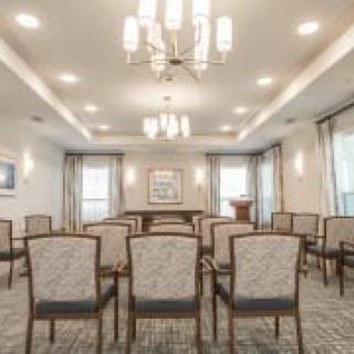A well-lit conference room with arranged chairs facing a podium and decorative lighting.