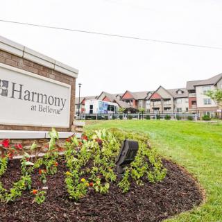A landscaped area with a sign reading 'Harmony' in front of a residential building.