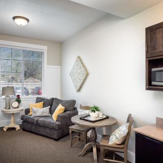 A cozy living room with a sofa, small dining table, and large window.