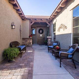 A cozy outdoor patio with seating leading to a front door entrance.