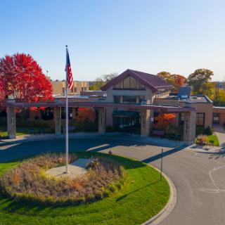 A healthcare facility showcasing autumn colors and a flag in front.