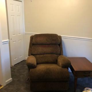 A cozy brown recliner next to a side table in a corner of the room.