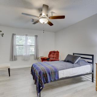 A minimalist bedroom with a bed, chair, and window with curtains.