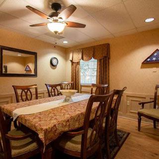 A cozy dining room with a long table, chairs, and warm lighting.