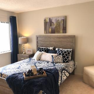 A cozy bedroom with a stylish bed, decorative pillows, and modern artwork.