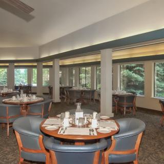 A spacious dining room with set tables and large windows.