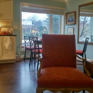 A cozy living room featuring a red upholstered chair and large windows letting in natural light.