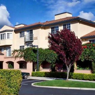 A suburban residential building surrounded by well-maintained landscaping and trees on a sunny day.
