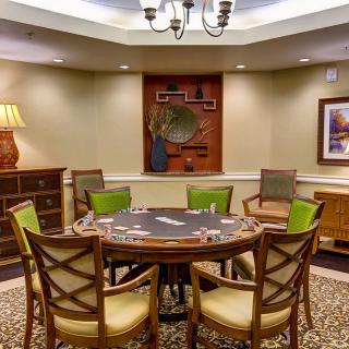 A well-decorated dining room with a round table and chairs, featuring elegant lighting and decor.