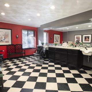 A stylish barber shop featuring a modern design with red walls and a classic black and white checkered floor.